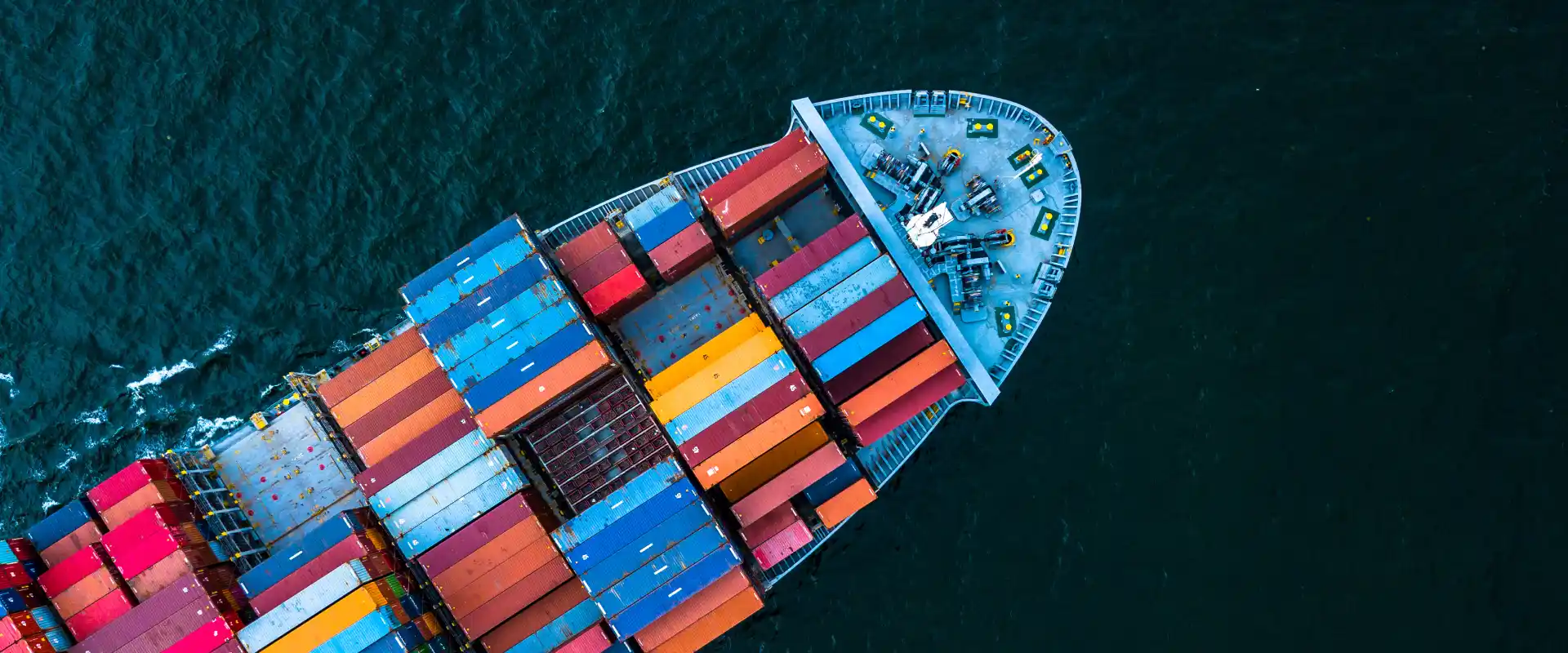 Vogelperspektive eines Containerschiffs mit bunten Containern, das auf dem offenen Meer fährt